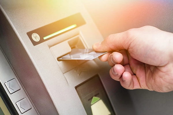 Person sliding credit card into atm